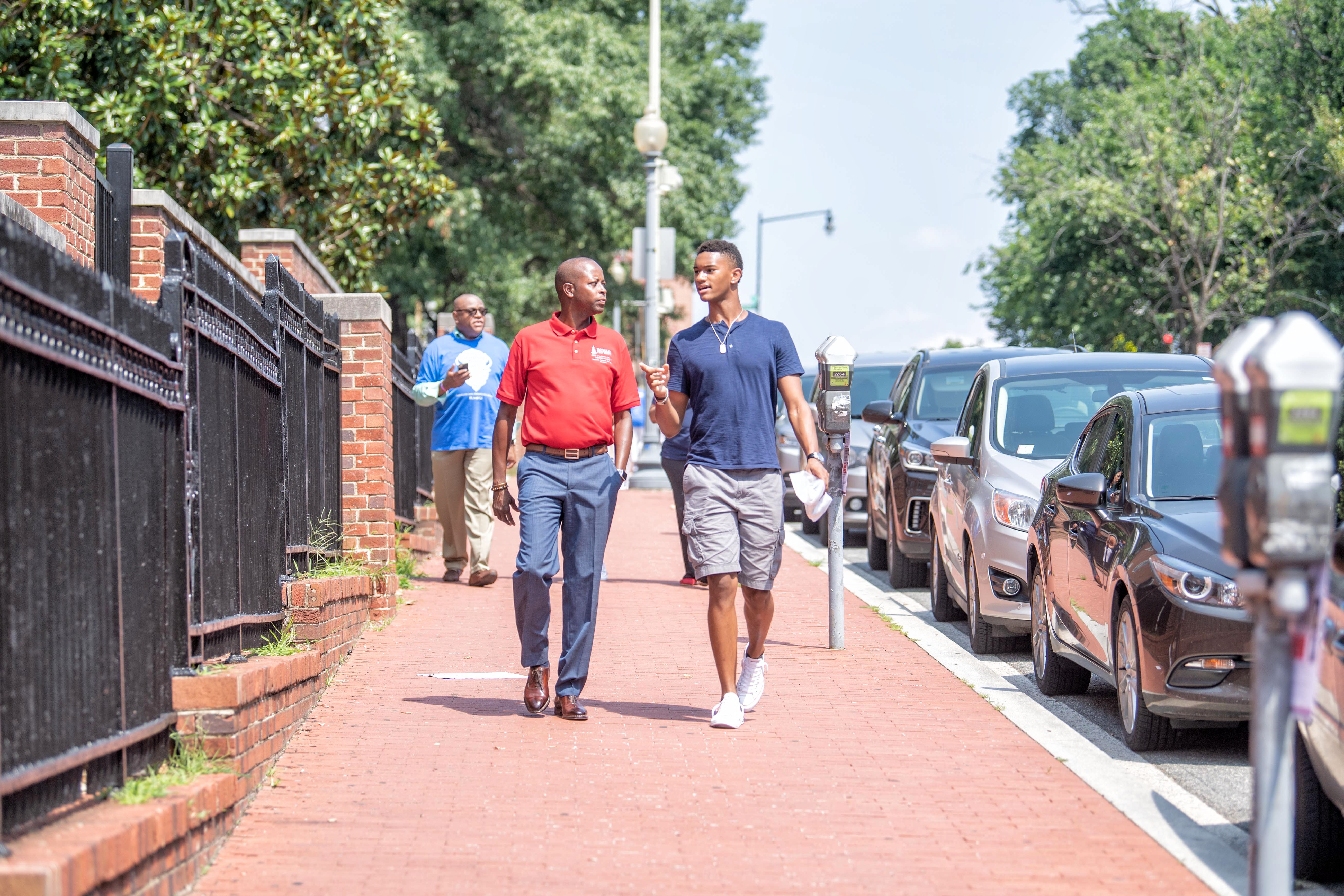 President Frederick walking on campus with a student.